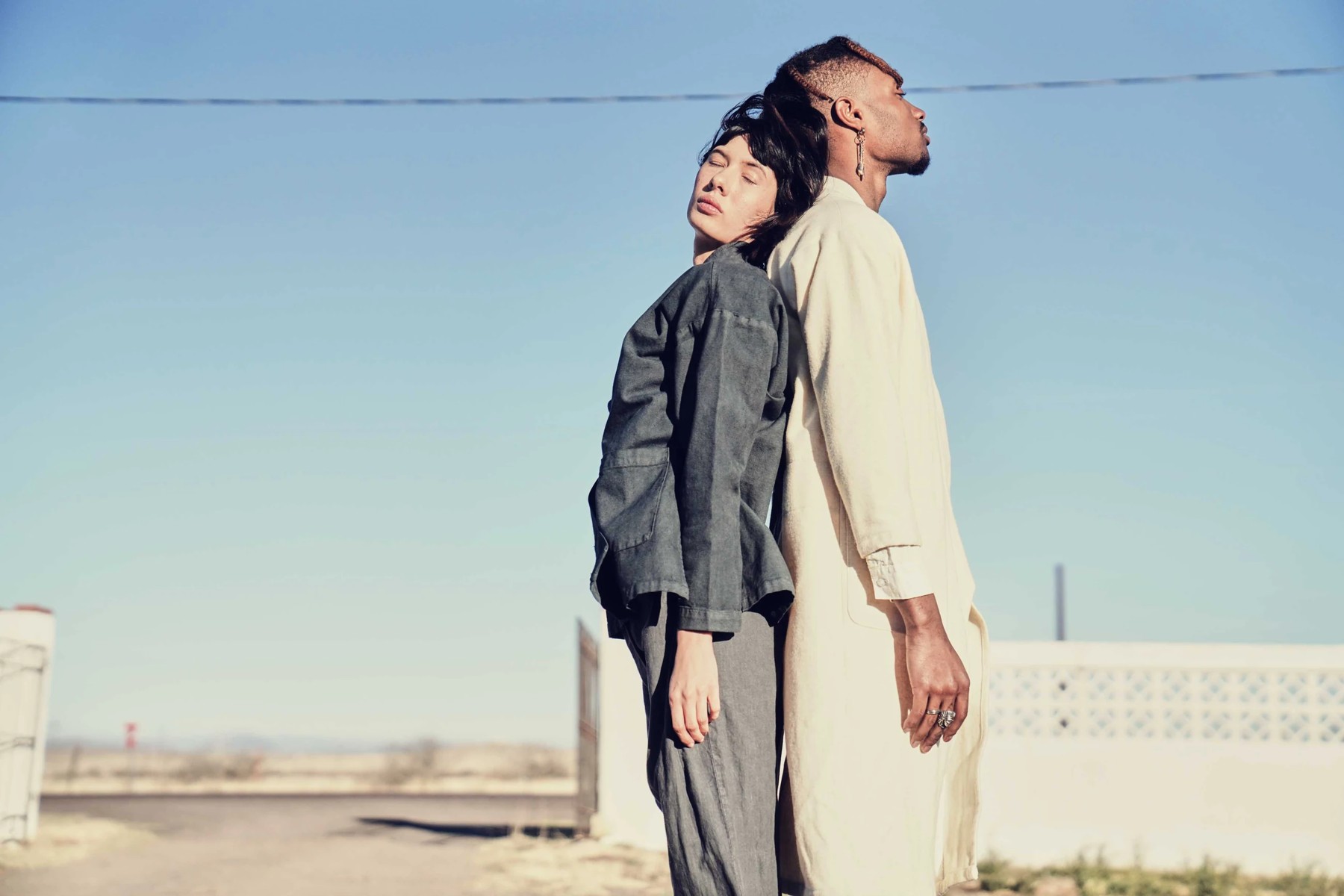 Two fashion models beneath a clear blue sky
